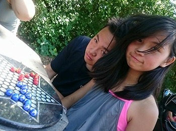Two campers, a boy and a girl, sitting outdoors and focusing intently on a game of Chinese Checkers during a break at summer camp.