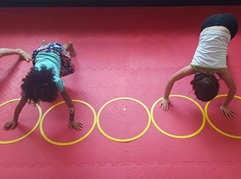 Kids practicing agility and coordination drills using floor hoops at a March break camp for kids in Burlington.
