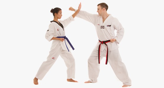A female martial artist with a blue belt blocking a punch from a male martial artist with a black and red belt during a self-defense drill.