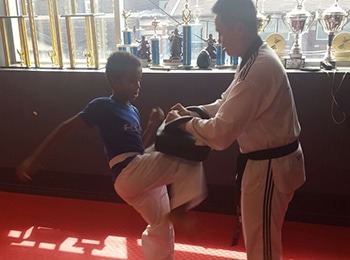 A young student practicing a martial arts strike with an instructor during a taekwondo march break program for children in Burlington.