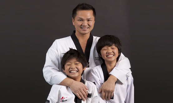 A heartwarming portrait of "Master Chang" with junior students, highlighting the positive mentorship, community, and fun environment found at the martial arts school.