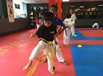 : A diverse group of smiling children posing in martial arts uniforms during a fun and safe March break camp for kids in Burlington.